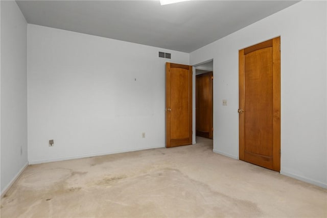 interior space featuring visible vents, light colored carpet, and baseboards