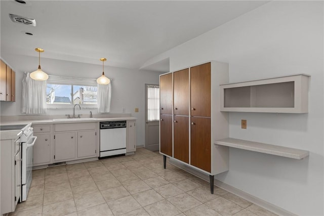 kitchen featuring visible vents, pendant lighting, light countertops, white appliances, and a sink