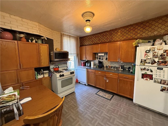 kitchen with dark countertops, brown cabinets, white appliances, a textured ceiling, and a sink