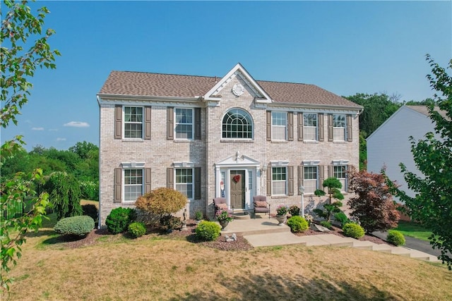 colonial-style house with brick siding and a front lawn