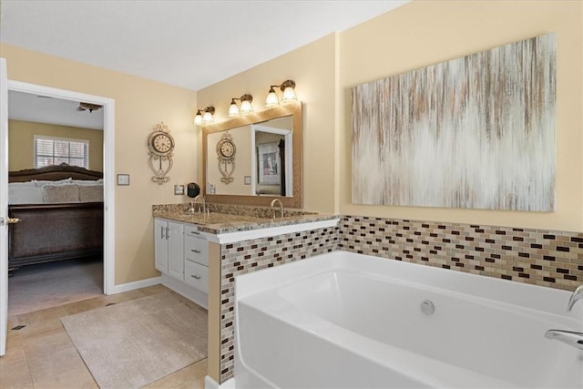 bathroom with tile patterned floors, a garden tub, ensuite bath, double vanity, and baseboards