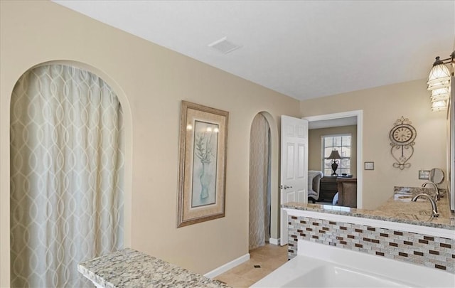 bathroom with ensuite bath, a tub to relax in, baseboards, and tile patterned floors