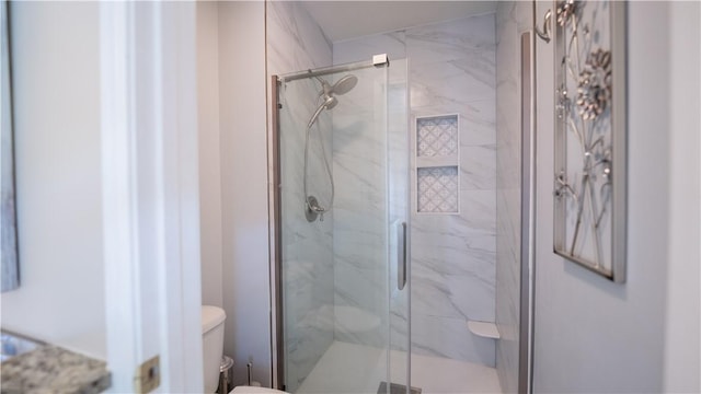 bathroom with a marble finish shower and toilet