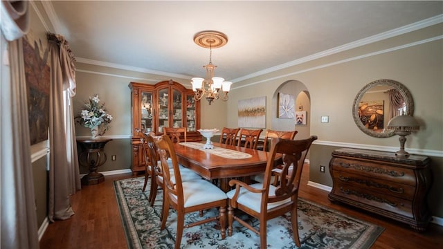 dining space with dark wood-type flooring, baseboards, ornamental molding, an inviting chandelier, and arched walkways