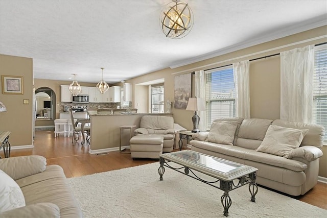 8004 Maureen Dr, Cranberry Twp, PA 16066 - living room with wood finished floors, arched walkways, a chandelier, and baseboards