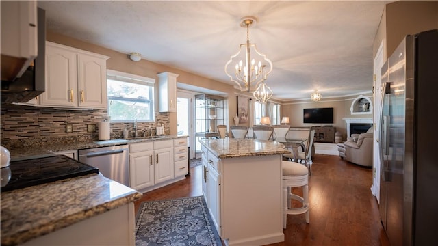 kitchen with a breakfast bar area, an inviting chandelier, white cabinets, appliances with stainless steel finishes, and open floor plan