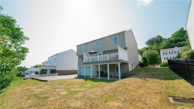 back of house with a lawn, an attached garage, driveway, and fence