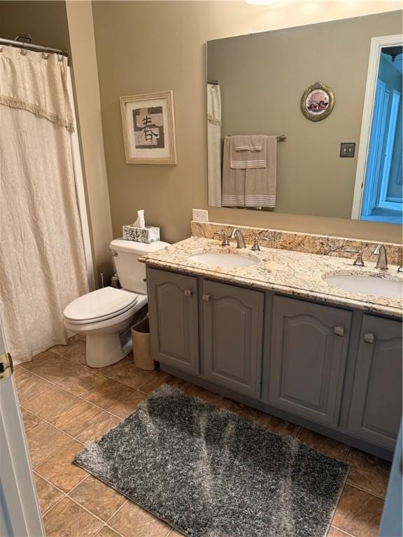 bathroom with double vanity, a sink, tile patterned floors, and toilet
