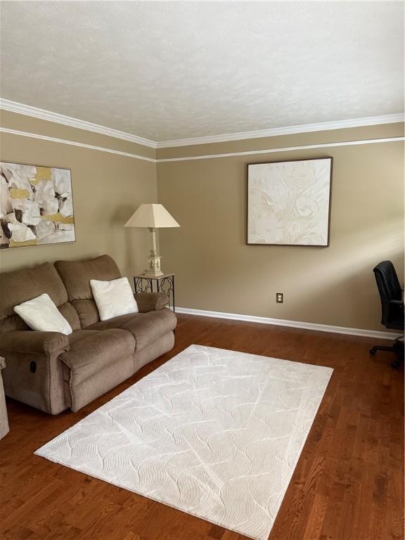 living room featuring crown molding, baseboards, and wood finished floors