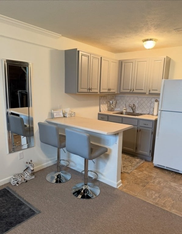 8004 Maureen Dr, Cranberry Twp, PA 16066 - kitchen with freestanding refrigerator, gray cabinets, a sink, a breakfast bar area, and tasteful backsplash