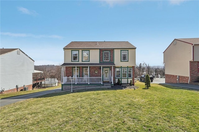 view of front facade featuring brick siding, cooling unit, a porch, and a front yard