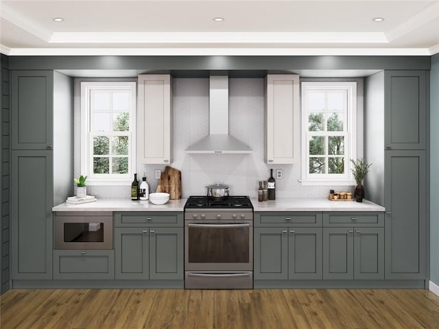 kitchen with built in microwave, gas range, gray cabinetry, and wall chimney range hood