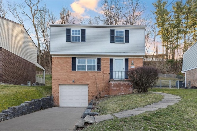 colonial house with driveway, a front lawn, fence, an attached garage, and brick siding