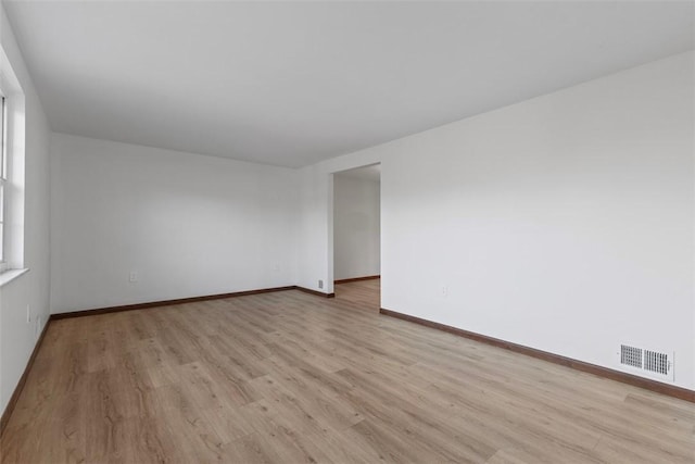 unfurnished room with baseboards, visible vents, and light wood finished floors