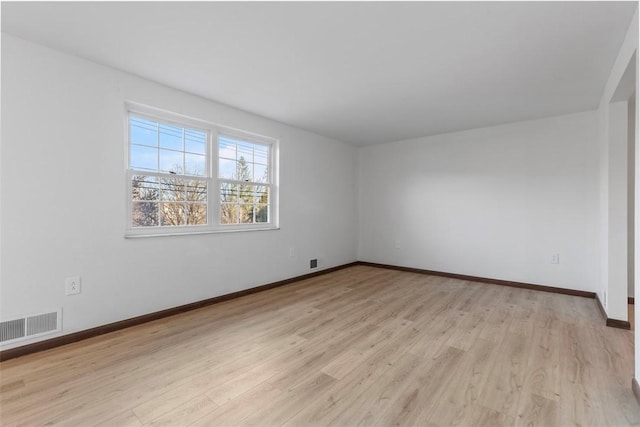 unfurnished room with visible vents, light wood-style flooring, and baseboards