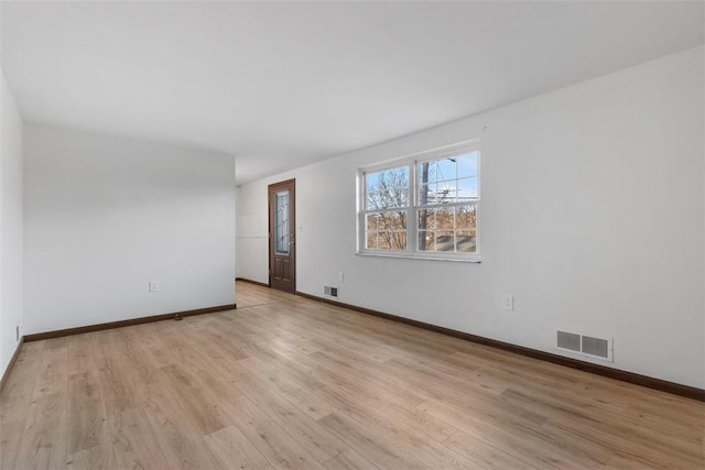 empty room featuring visible vents, baseboards, and light wood-style floors