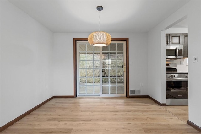 unfurnished dining area featuring light wood-type flooring, visible vents, and baseboards