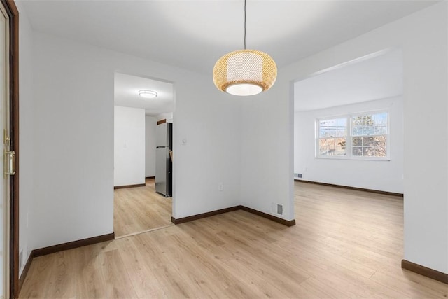 empty room with visible vents, baseboards, and light wood-type flooring