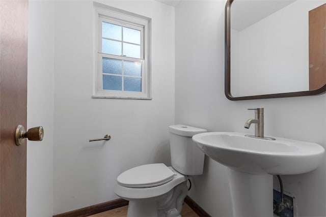 half bathroom with toilet, baseboards, and wood finished floors