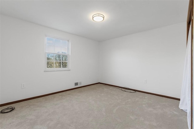 carpeted spare room featuring visible vents and baseboards