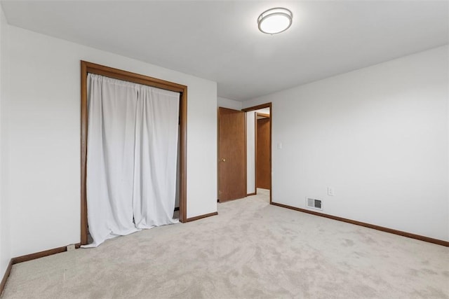 unfurnished bedroom featuring visible vents, light carpet, baseboards, and a closet