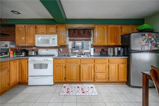 kitchen featuring visible vents, light tile patterned floors, brown cabinetry, white appliances, and a sink