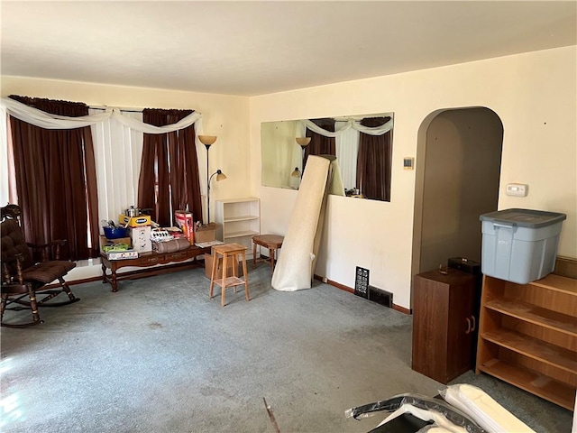 living area featuring carpet, arched walkways, and baseboards