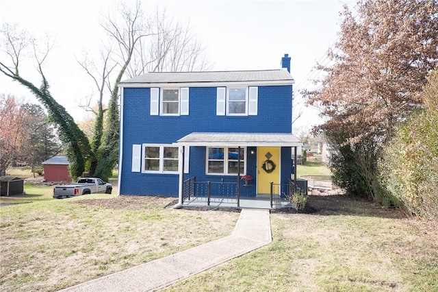 traditional-style home featuring a front lawn, brick siding, covered porch, and a chimney