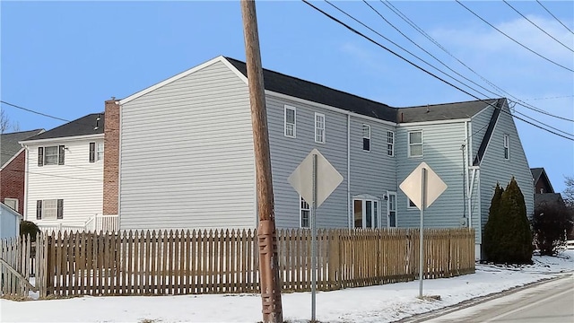 view of snow covered exterior with fence