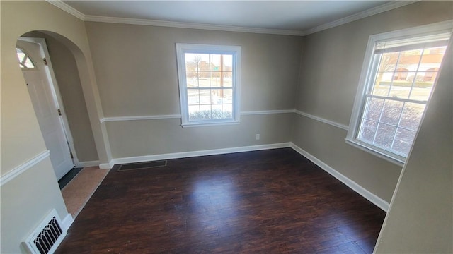 spare room with arched walkways, visible vents, plenty of natural light, and wood finished floors