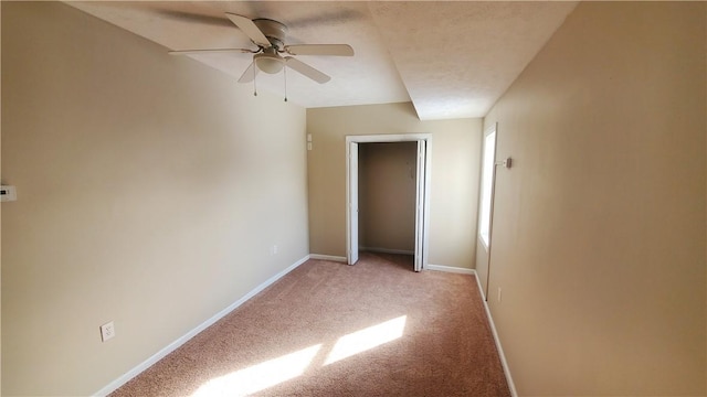 spare room featuring light colored carpet, baseboards, and ceiling fan