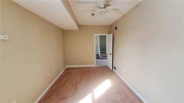 carpeted spare room featuring visible vents, baseboards, and ceiling fan