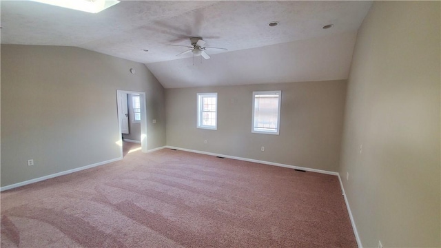 unfurnished room with vaulted ceiling, a ceiling fan, baseboards, and carpet floors