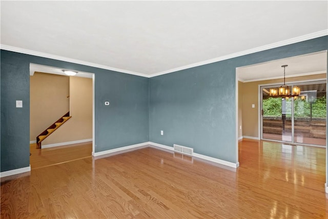 spare room featuring visible vents, a notable chandelier, wood finished floors, and baseboards