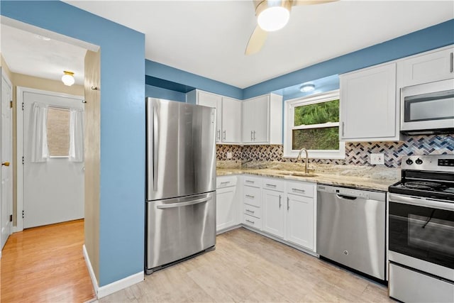 kitchen featuring a sink, stainless steel appliances, backsplash, and white cabinetry