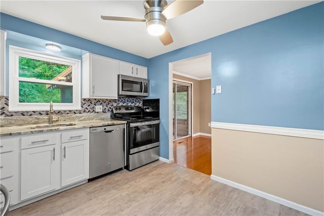 kitchen featuring decorative backsplash, appliances with stainless steel finishes, white cabinetry, and a sink