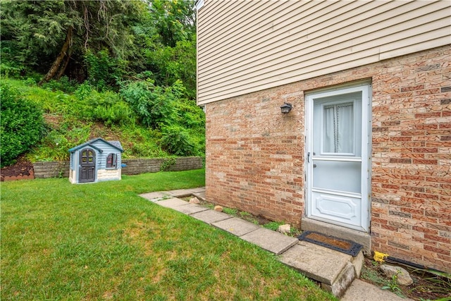 doorway to property featuring a yard and brick siding