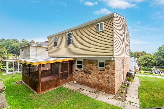 back of house featuring a yard, brick siding, cooling unit, and a sunroom