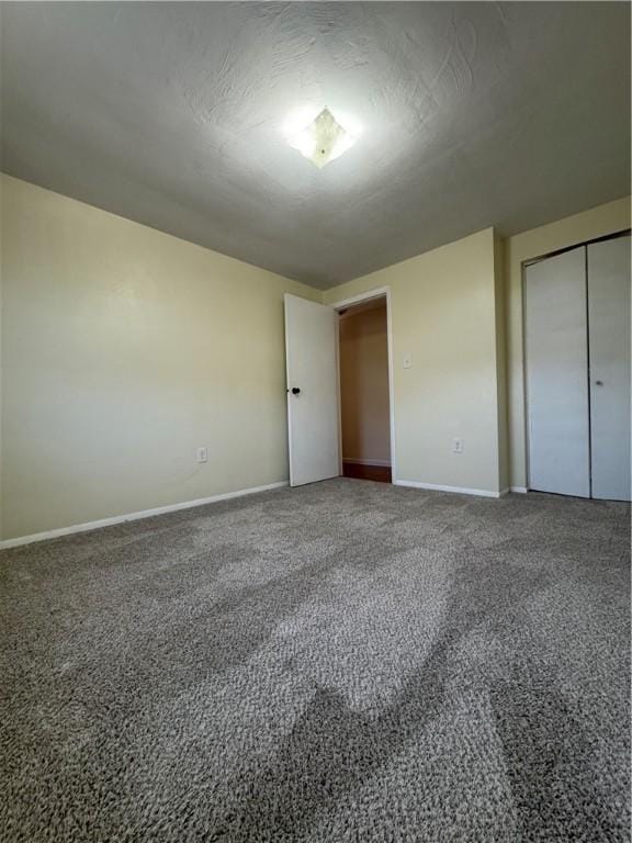 unfurnished bedroom featuring a closet, carpet flooring, a textured ceiling, and baseboards