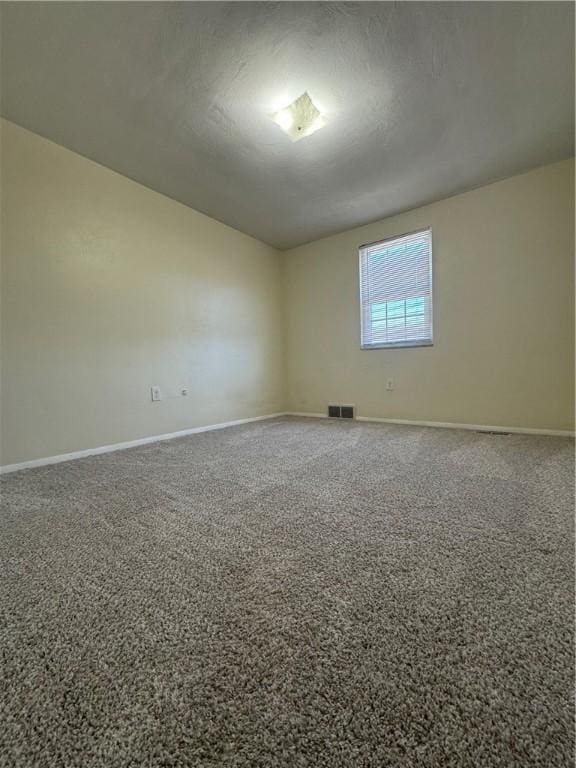 spare room featuring baseboards, visible vents, and a textured ceiling