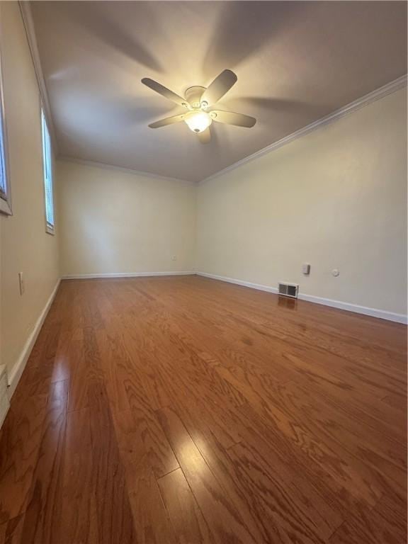 unfurnished room with wood finished floors, baseboards, visible vents, ceiling fan, and crown molding