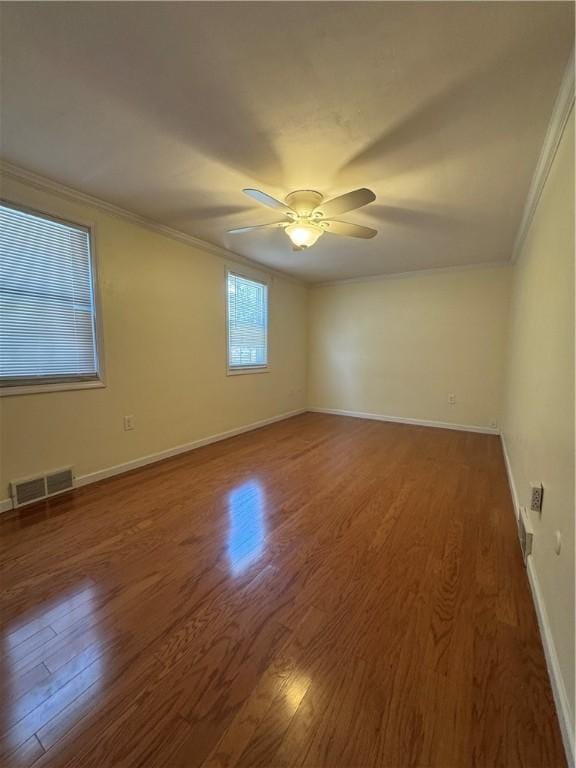 spare room with visible vents, baseboards, ornamental molding, wood finished floors, and a ceiling fan