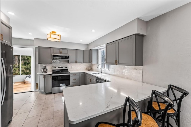 kitchen with gray cabinets, a sink, freestanding refrigerator, a peninsula, and stainless steel electric range oven