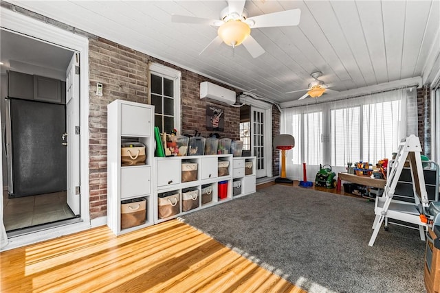 game room with wood finished floors, a ceiling fan, brick wall, a wall mounted AC, and wood ceiling