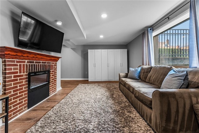 living room featuring recessed lighting, a fireplace, baseboards, and wood finished floors