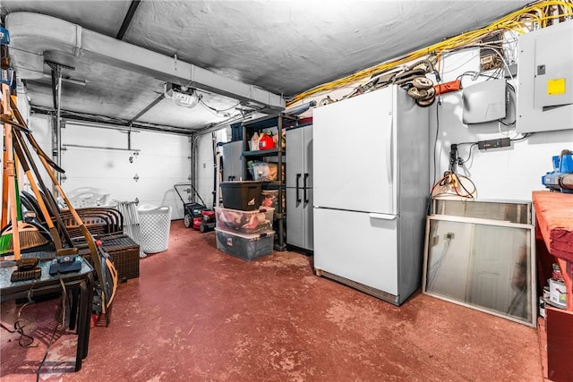 garage featuring electric panel, a garage door opener, and freestanding refrigerator