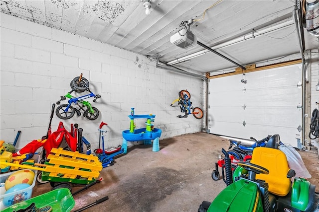 garage with a garage door opener and concrete block wall