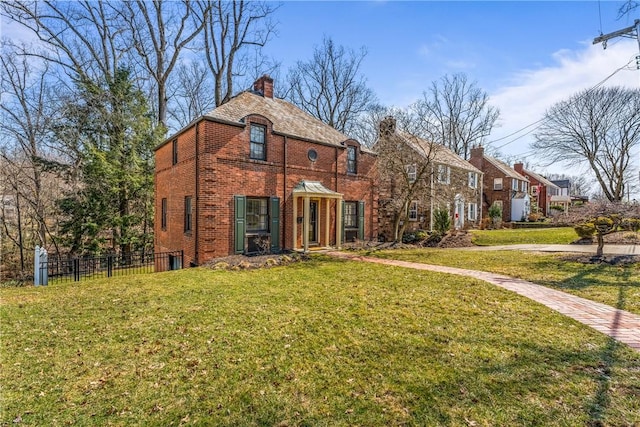 view of front of home with brick siding, a chimney, a front lawn, and fence