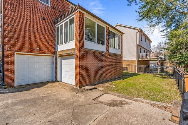 view of property exterior featuring fence, driveway, a garage, a lawn, and brick siding