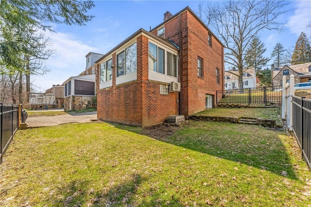 exterior space featuring a chimney, a fenced backyard, brick siding, and a lawn